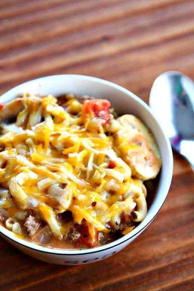 close up of cheesy beef skillet dinner in a bowl with spoon on the side