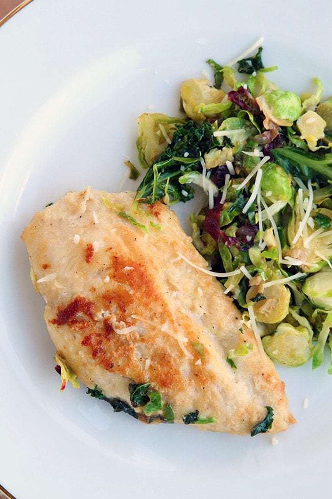 white plate with Chicken, Kale and Brussel Sprouts on side