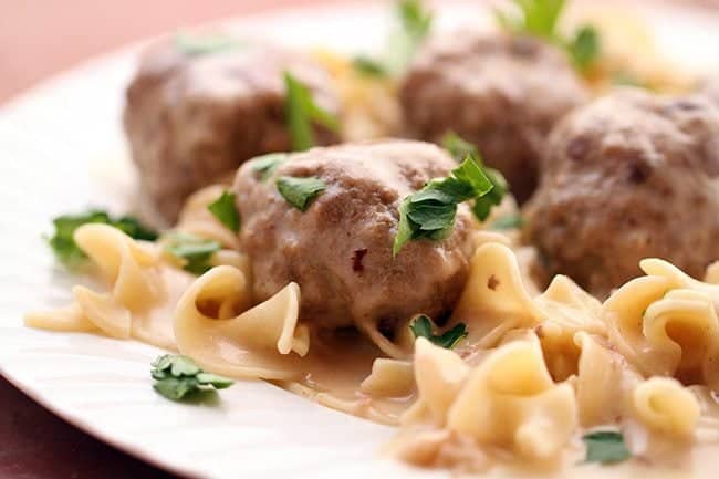 Close up Turkey Swedish Meatballs served over egg noodles garnished with parsley leaves