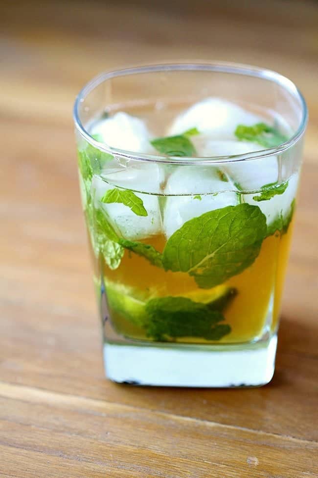 Close up of Maple Whiskey Mojito in a whisky glass with ice, mint leaves and slice of lime