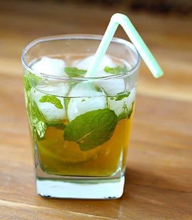 Maple Whiskey Mojito in a whisky glass with mint leaves and slice of lime on wood background