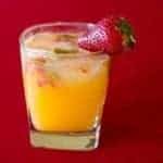Close up of Short Glass with Tangerine & Gin Garnish with a Piece of Fresh Strawberry on Red Background