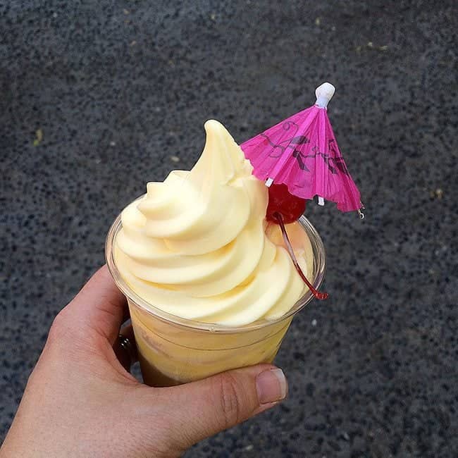 Dole Whip in a cup with pink cocktail umbrella and a cherry