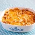 White Bean Ranch, Bacon & Cheddar Dip in a white casserole dish on a blue printed tablecloth