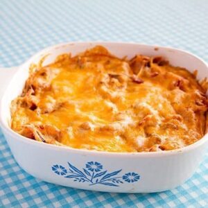 White Bean Ranch, Bacon & Cheddar Dip in a white casserole dish on a blue printed tablecloth
