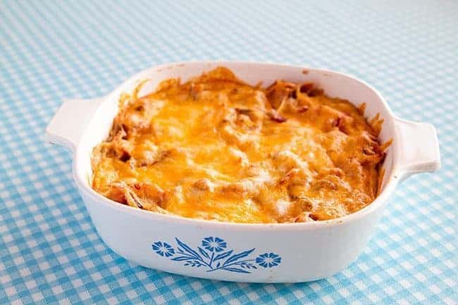 White Bean Ranch, Bacon & Cheddar Dip in a white casserole dish on a blue printed tablecloth