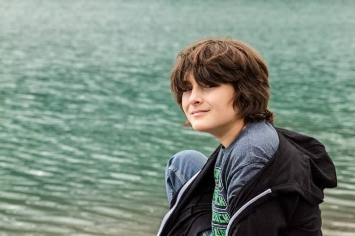 young boy wearing shirt and black jacket near the sea