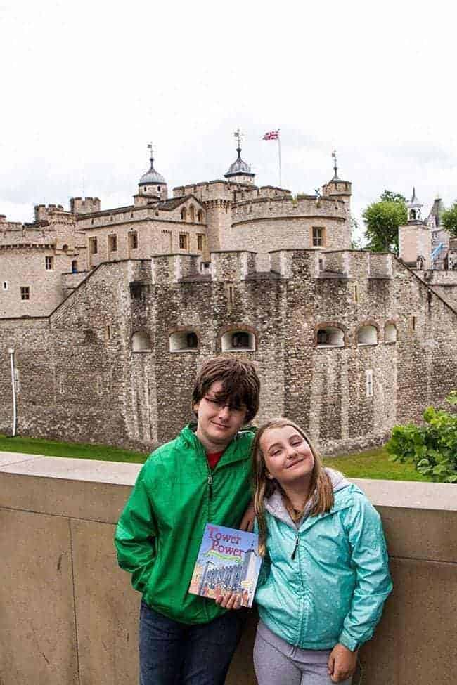 kids picture holding a book with the background of Tower of London