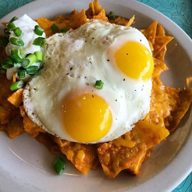a plate of chilaquiles topped with eggs and chopped green onions