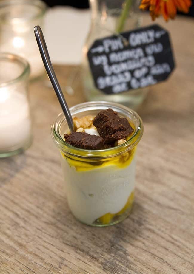 A cup of yogurt with chocolate brownies, mango and walnuts