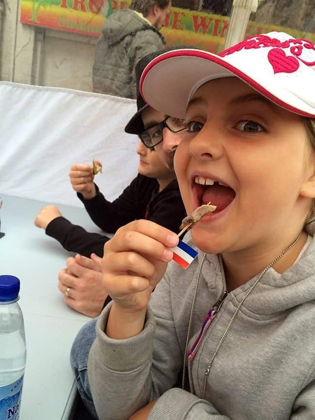 young girl in grey jacket act like eating the herring