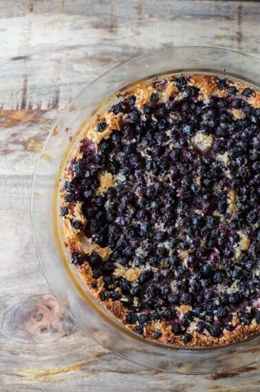 close up of Impossible Pie with Saskatoon Berries in a Pyrex pie dish on wood background