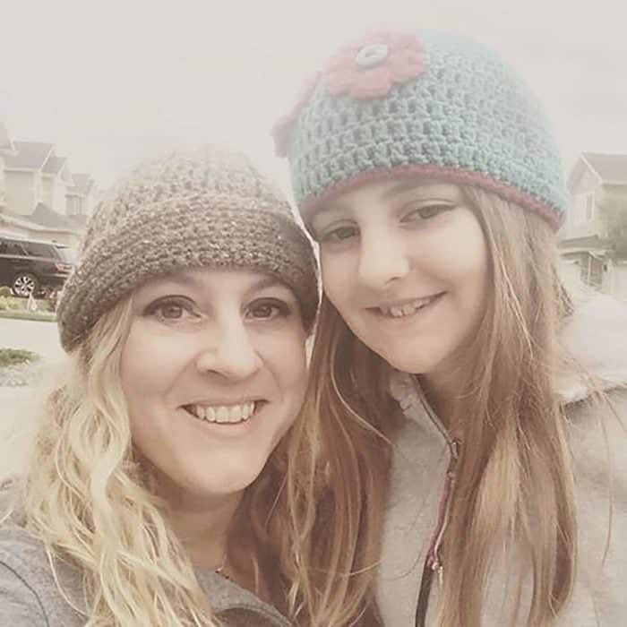 smiling mother and daughter with long hair wearing beanie hat 