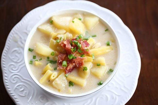 Creamy Yellow Bean & Potato Soup in a white soup bowl over white plate with engraves