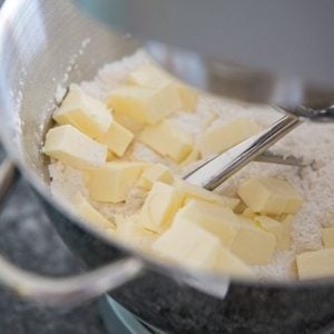 fatias de manteiga numa tigela misturadora, com farinha e outros ingredientes para Scones de cereja natalícia