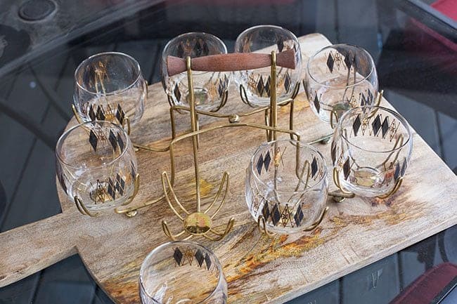 a set of retro shot glasses arranged in its holder over a wood board