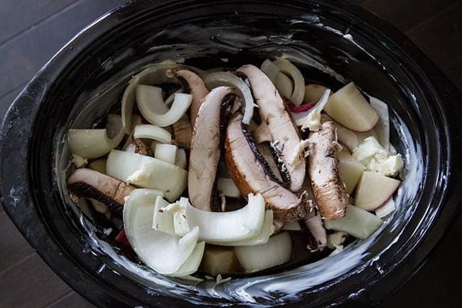 Crockpot with Flat Iron Steak, Portobello Mushrooms, Potatoes and beef broth ready for cooking