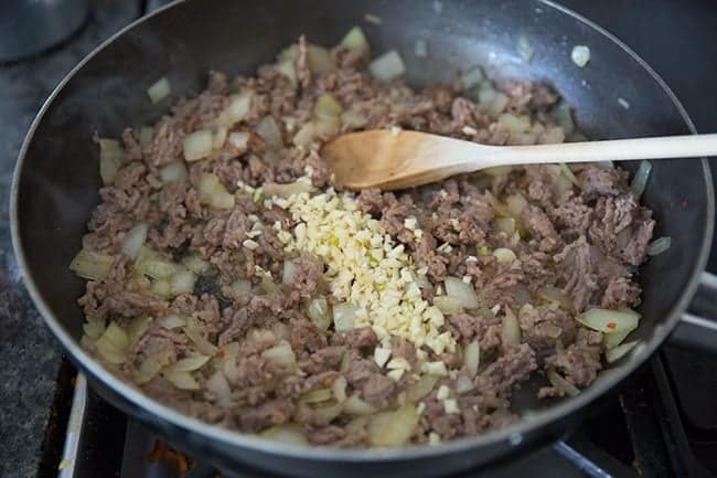 frying the ground sausage and onions in a large skillet using a wooden spoon