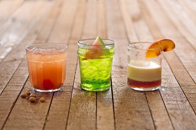 short glasses with different drinks on wood background