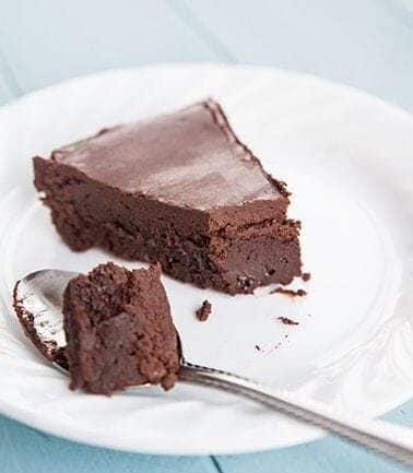 a spoon with Chocolate cake and a slice of Flourless Chocolate Cake in a white plate