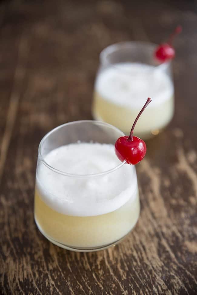 Close up of Two glasses of Smoky Whisky Sour Garnish with Cherry on Wood background