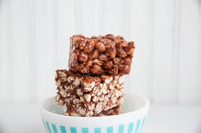 Stacks of Chewy Chocolate Puffed Wheat Squares in White Bowl on White Background