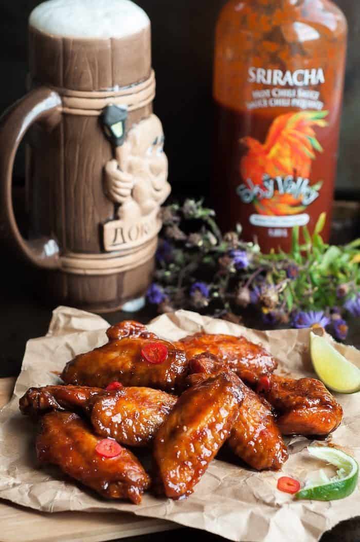 Crispy Honey Sriracha Wings, beer mug and a bottle of Sriracha at the back 