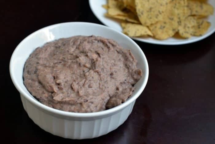 Quick Black Bean Dip in white ramekins and a plate of tacos beside it 