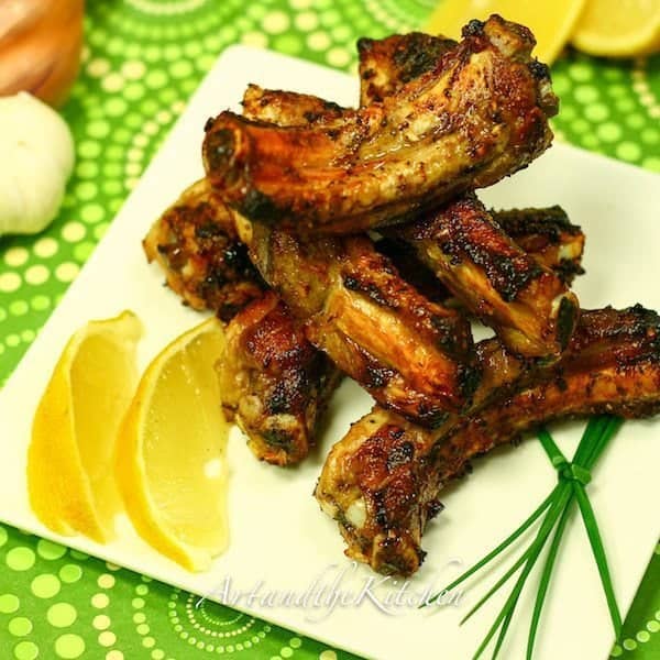 Greek Ribs in a white square plate garnish with slices of lemon
