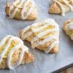 Close up of Triangle Shaped Glazed Meyer Lemon Scones in baking sheet with parchment paper
