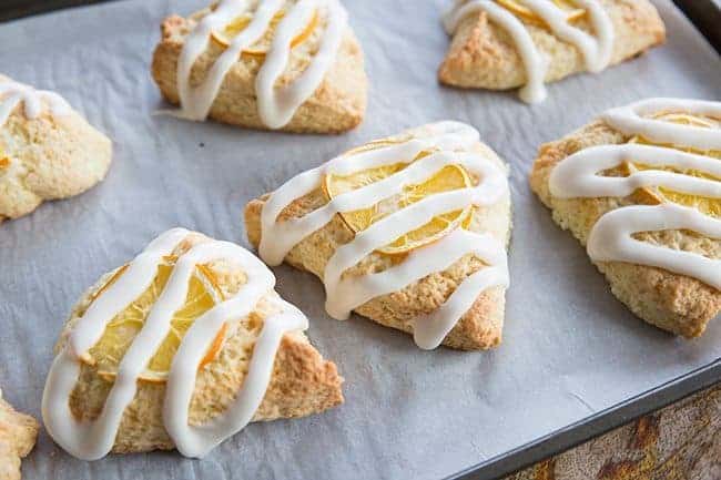Close up of Triangle Shaped Glazed Meyer Lemon Scones in baking sheet with parchment paper