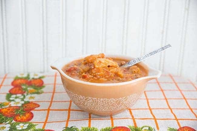 floral checkered tablecloth underneath a bowl of Ukrainian Cabbage Roll Soup with spoon on white background