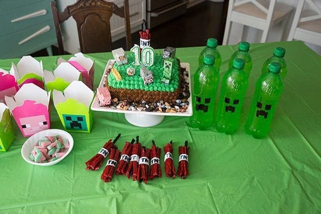 Top down shot of table with creeper green plastic tablecloth with Minecraft birthday party stuffs on top