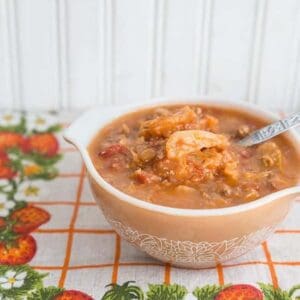Cabbage Roll Soup in a Pyrex bowl, a floral vintage tablecloth underneath and white background