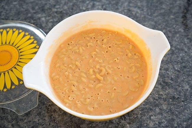 creamy vegetable mac n’ cheese with sauce in a Pyrex colored casserole