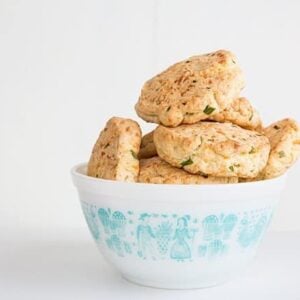 Bumpy shaped Cheddar & Chive Biscuits in white bowl on white background