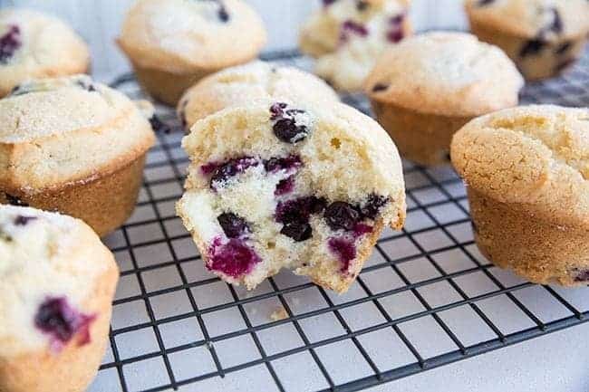 Blueberry Muffins in cooling rack. A half piece of blueberry muffin