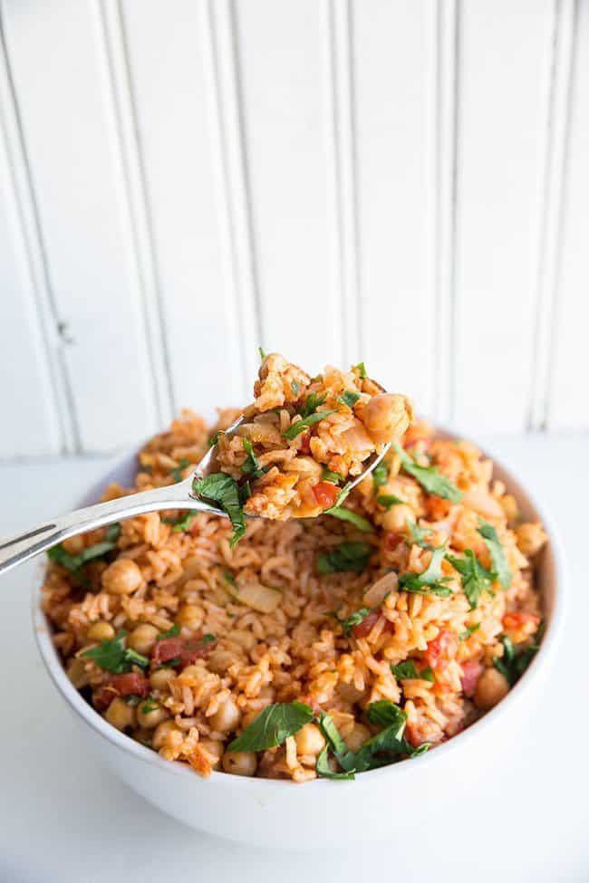 Spooning a Vegan Smoky Spanish Rice & Chickpeas with smoked paprika and freeze dried oregano