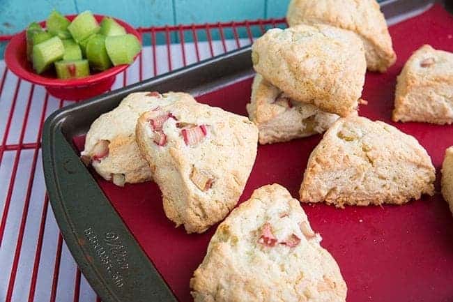 Coconut Rhubarb Scones on a red lined baking sheet over red cooling rack