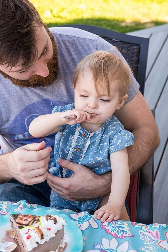 man holding his cute baby and letting her taste the cake from the spoon
