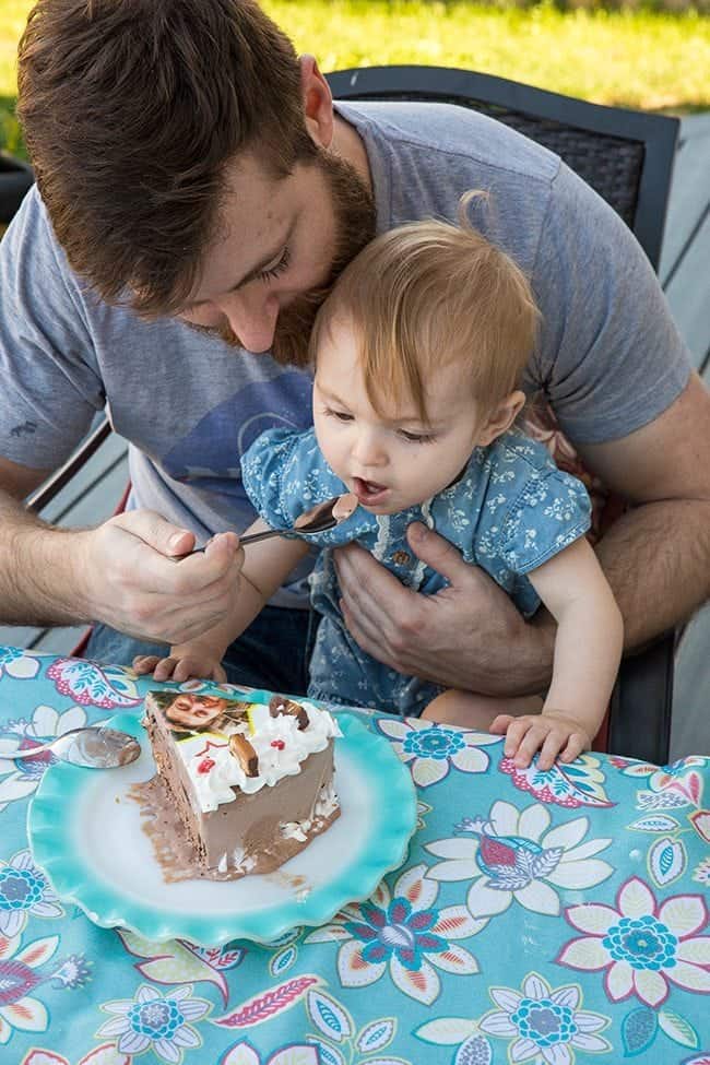 man feeding his little daughter with a bit of ice cream cake