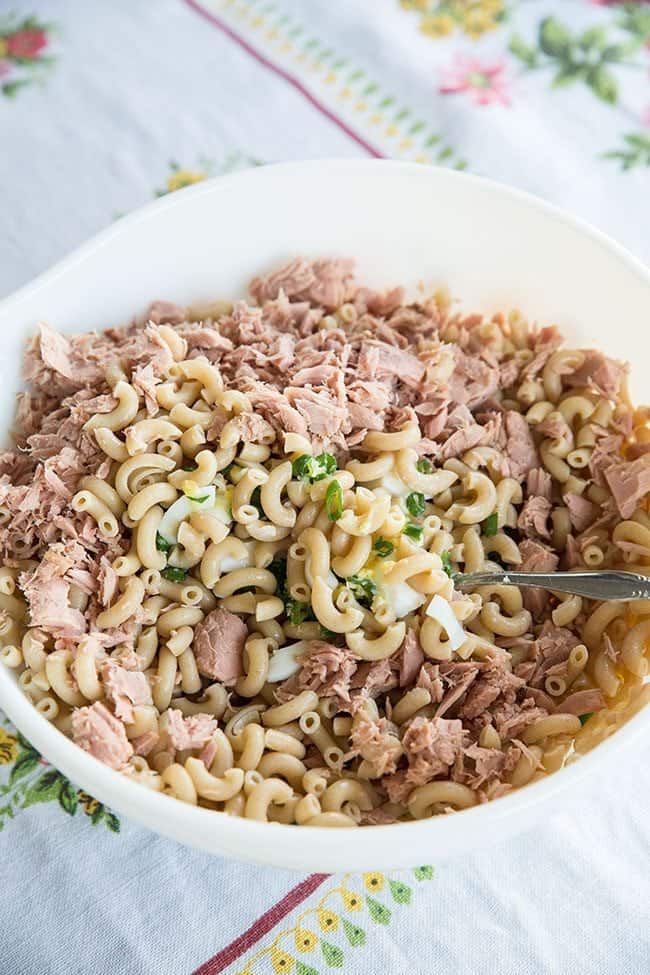 Stirring together the tuna salad ingredients in a large white bowl