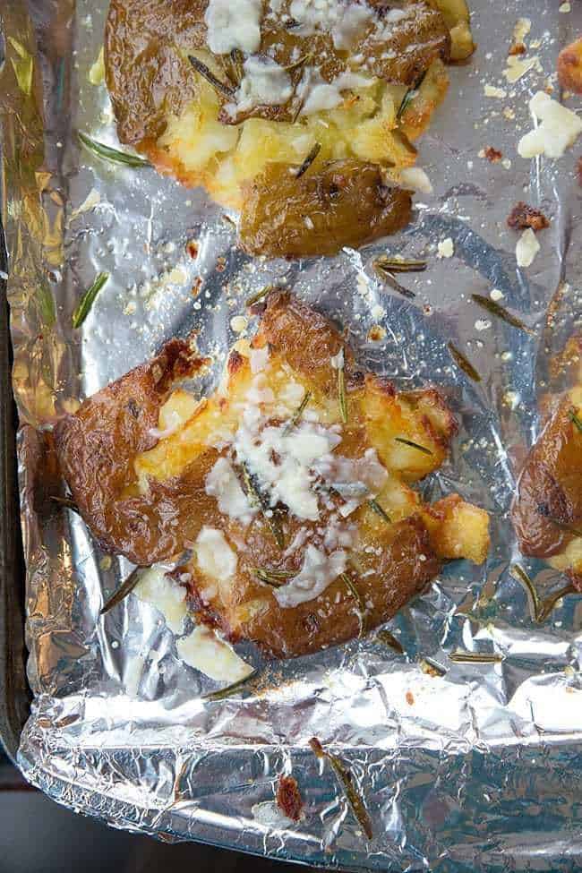 flat smashed potatoes with skin crisped up in a large baking sheet lined with tin foil