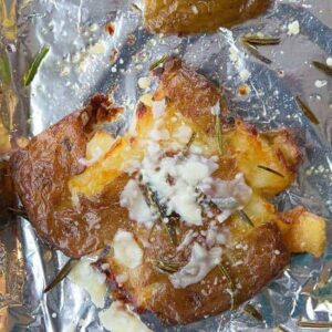 flat smashed potatoes with skin crisped up in a large baking sheet lined with tin foil
