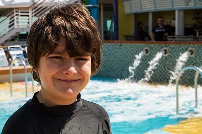 kid smiling in front of Royal Caribbean's Brilliance of the Seas Pool Bar