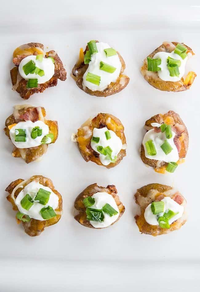 top down shot of Mini Loaded Smashed Potato Bites topped with sour cream, bacon, cheese and green onions on white background