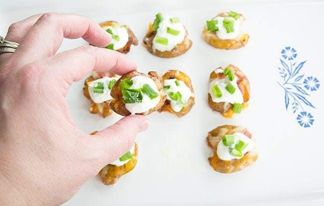 top down shot of Mini Loaded Smashed Potato Bites topped with sour cream, bacon, cheese and green onions