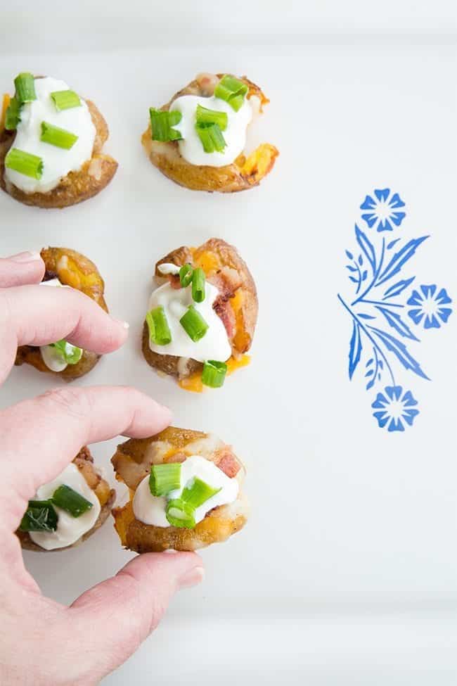 arranging the Mini Loaded Smashed Potato Bites in a white serving plate