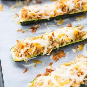 close up Cheesy Buffalo Chicken Zucchini Boats in a baking sheet lined with parchment paper