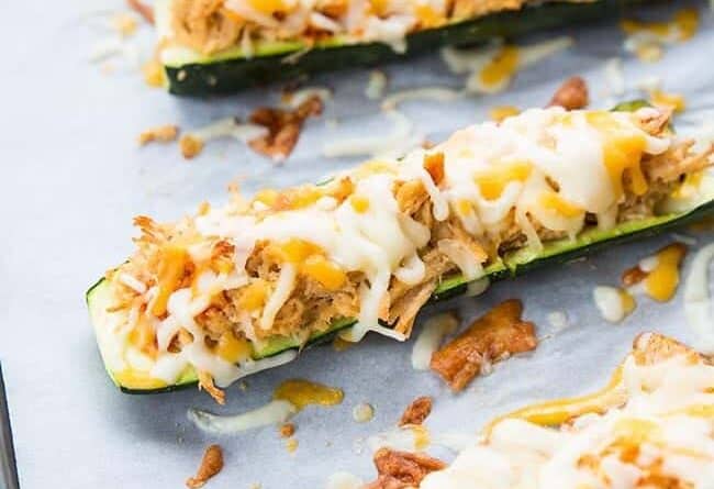 close up Cheesy Buffalo Chicken Zucchini Boats in a baking sheet lined with parchment paper